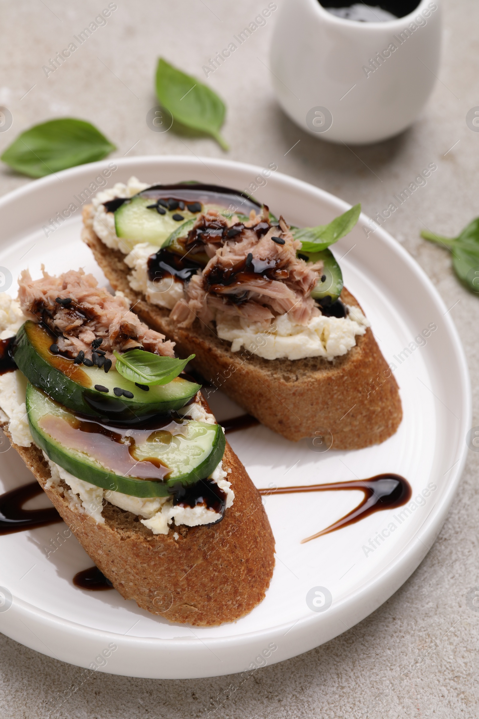 Photo of Delicious bruschettas with balsamic vinegar and toppings on light textured table