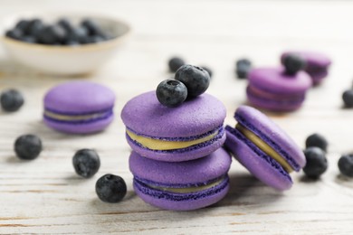 Photo of Delicious macarons and blueberries on white wooden table, closeup