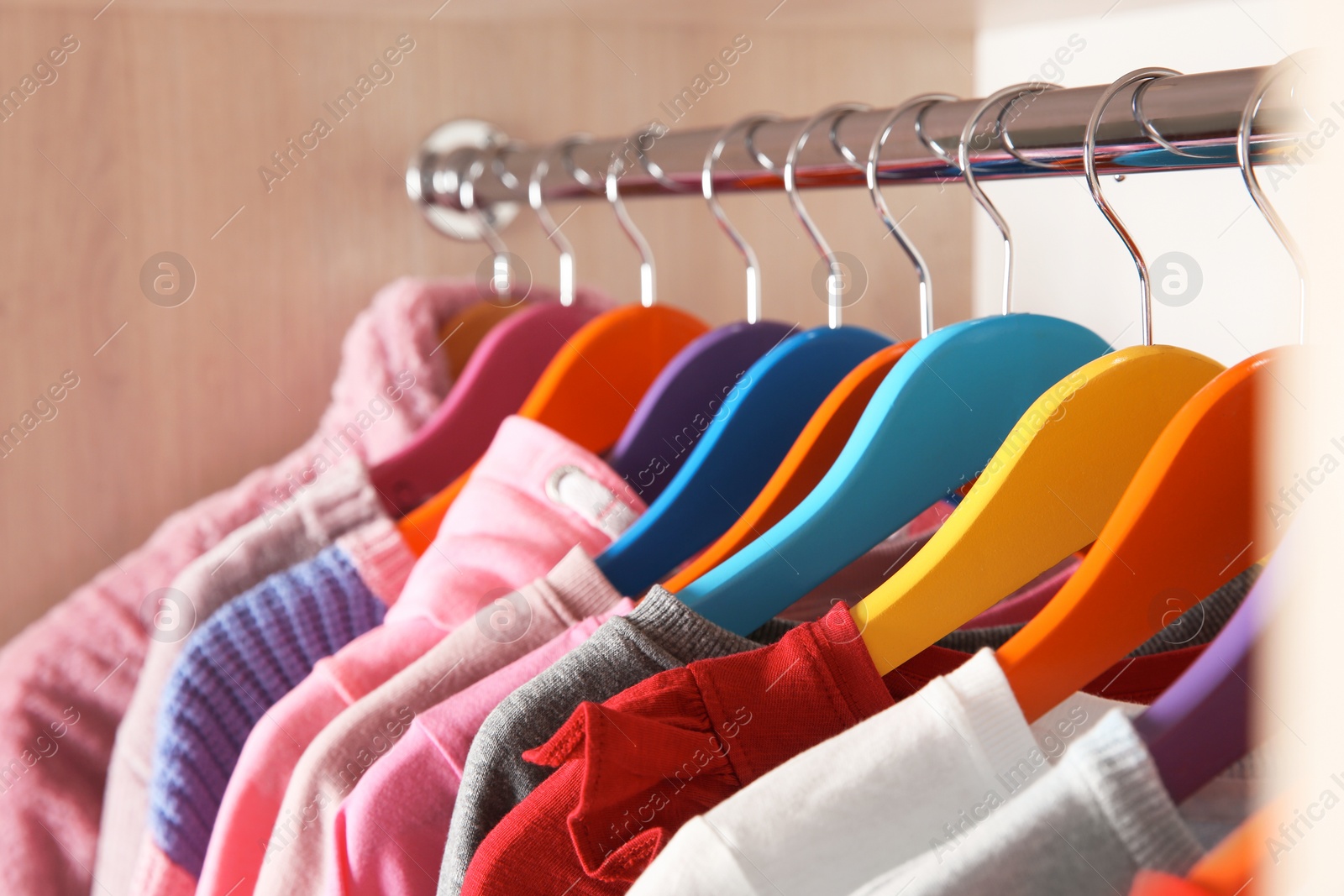 Photo of Stylish girl's clothes hanging in wardrobe, closeup