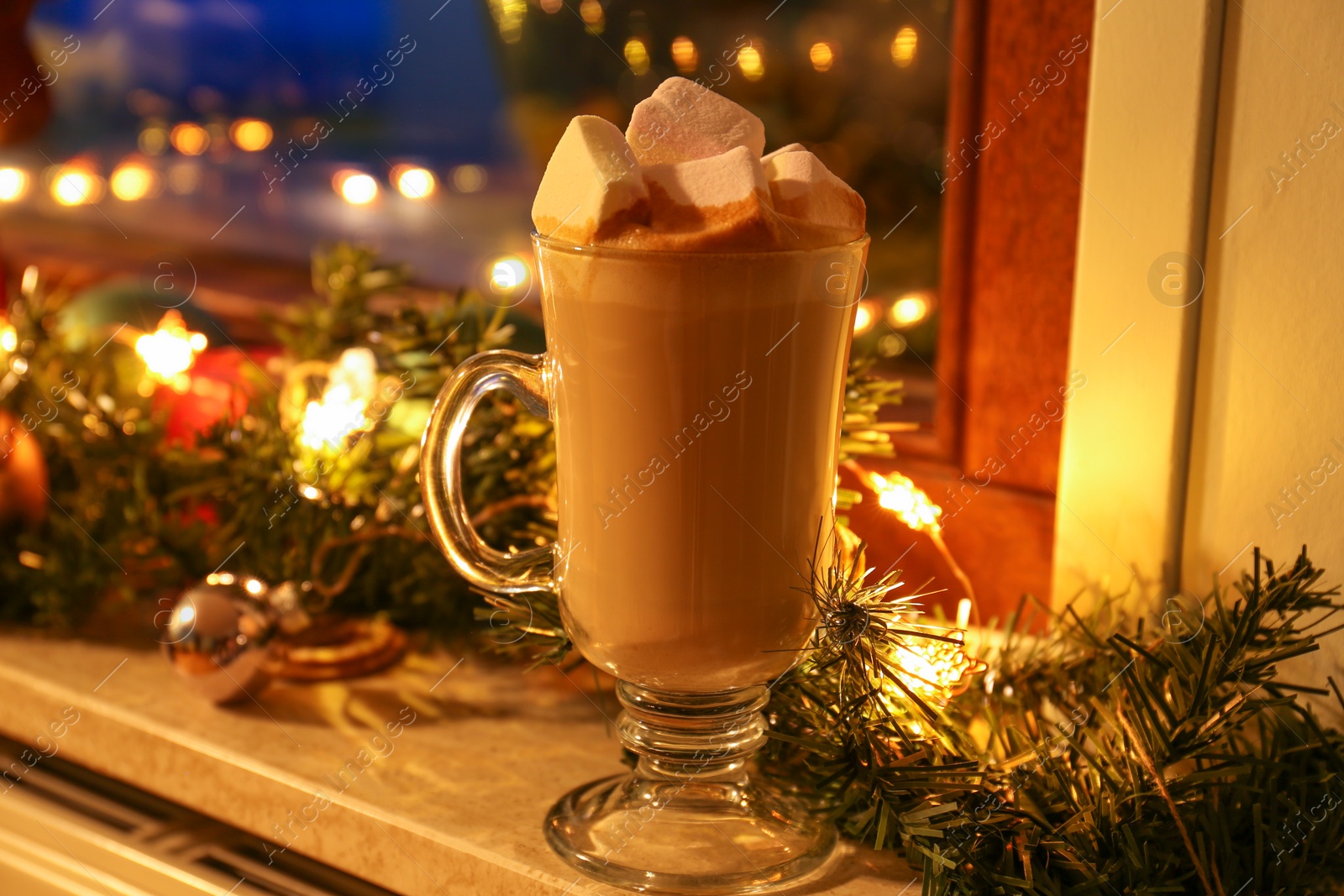 Photo of Glass of delicious hot cocoa with marshmallows and Christmas decoration on windowsill