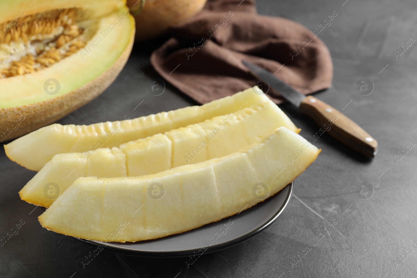 Photo of Slices of delicious honey melon on black table