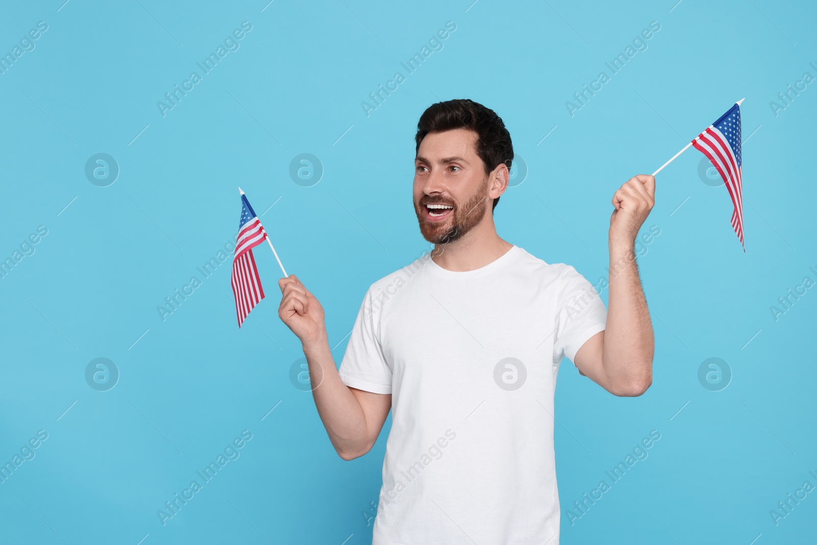 Photo of 4th of July - Independence Day of USA. Happy man with American flags on light blue background