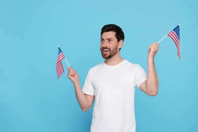 Photo of 4th of July - Independence Day of USA. Happy man with American flags on light blue background