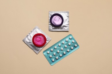 Contraception choice. Pills and condoms on beige background, flat lay
