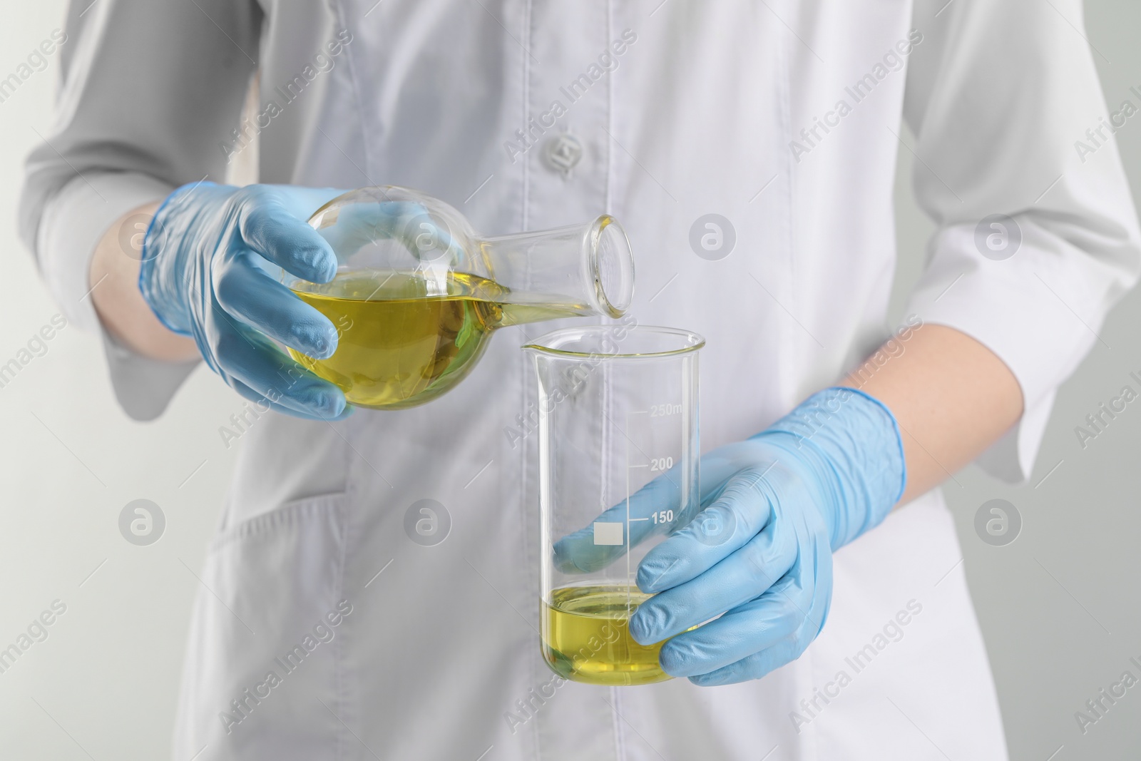 Photo of Scientist developing cosmetic oil on white background, closeup