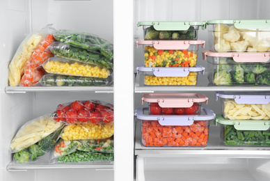 Plastic bags and containers with different frozen vegetables in refrigerator