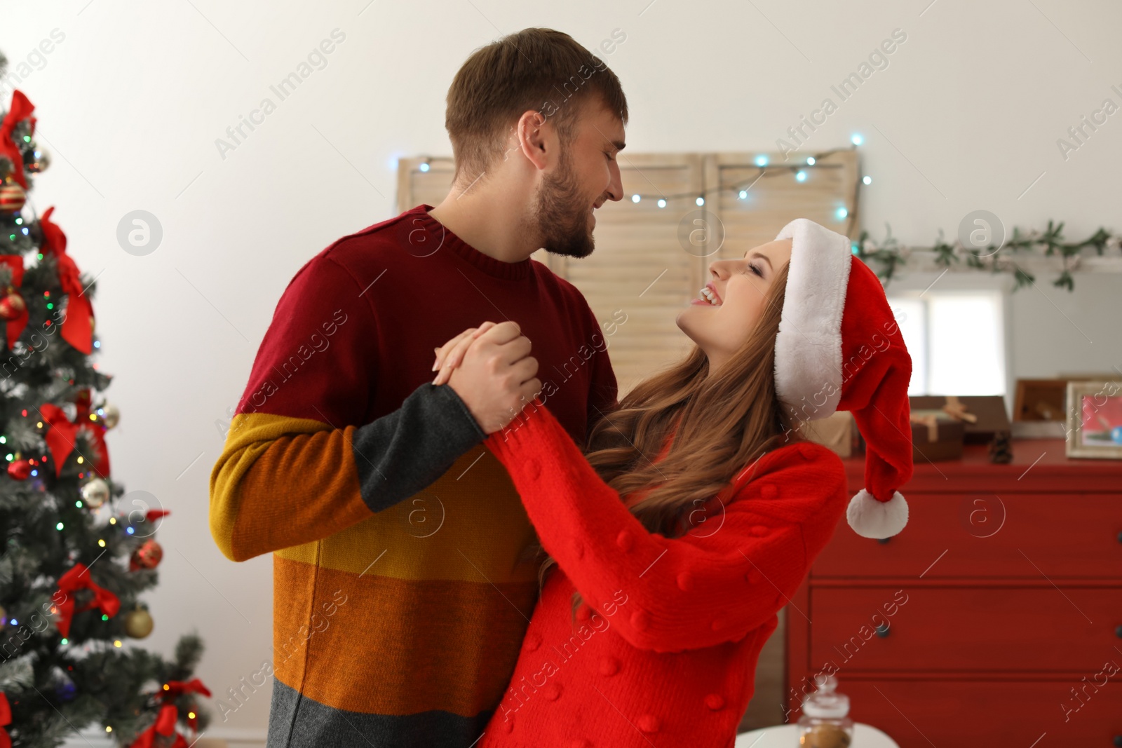 Photo of Happy young couple dancing near Christmas tree at home