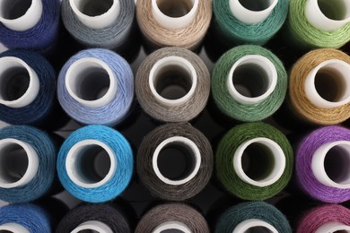 Photo of Set of colorful sewing threads as background, top view
