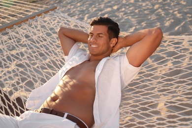 Photo of Man relaxing in hammock on beach at sunset