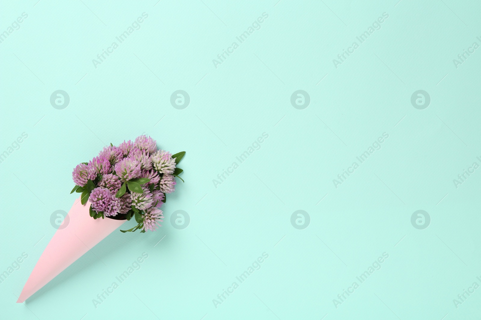 Photo of Bouquet of beautiful clover flowers on turquoise background, top view. Space for text