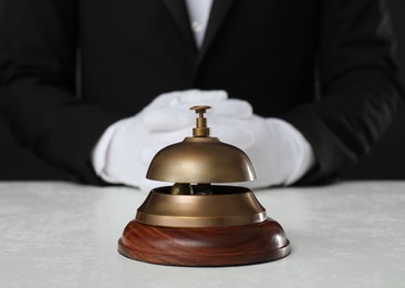 Photo of Butler at white desk with service bell, closeup view