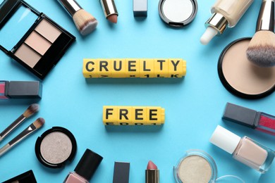 Photo of Cubes with text Cruelty Free and decorative cosmetics on turquoise background, flat lay. Stop animal tests