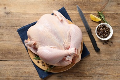 Photo of Fresh raw chicken with spices and knife on wooden table, flat lay