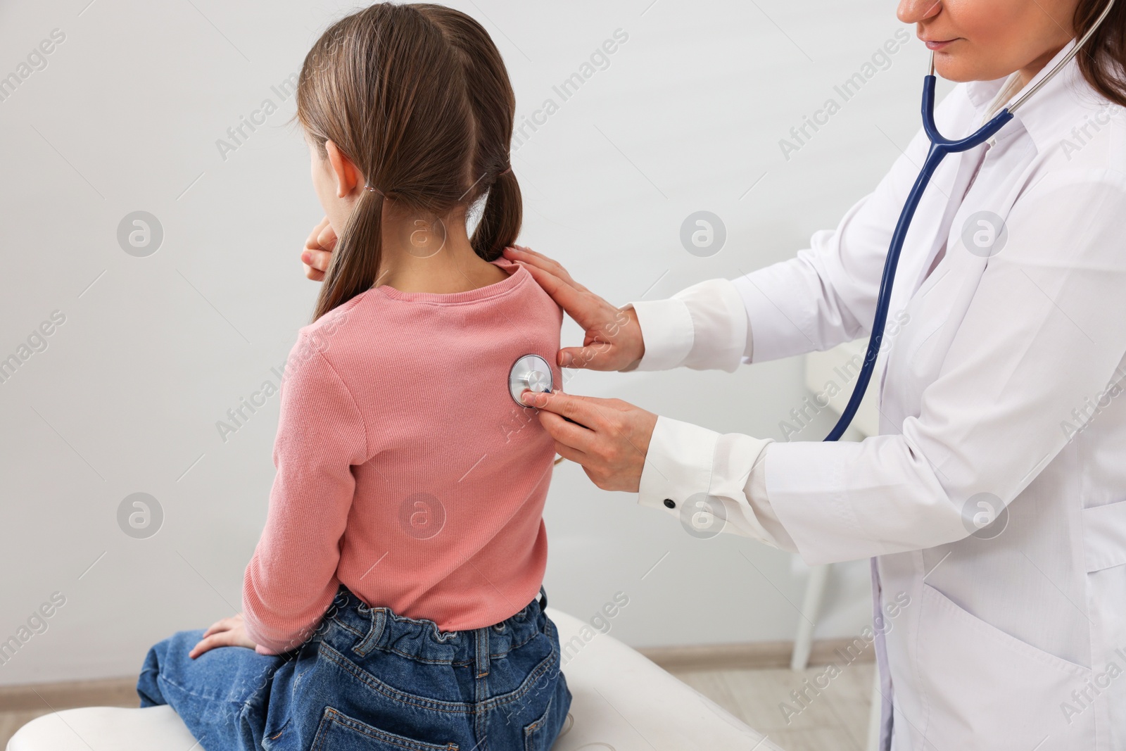 Photo of Doctor examining coughing girl in hospital. Cold symptoms