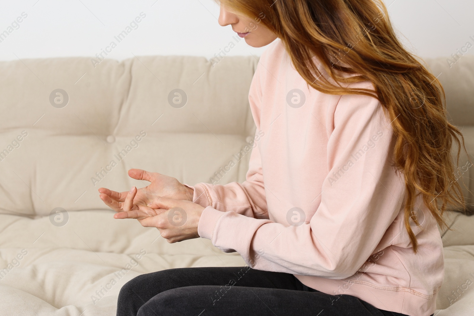 Photo of Woman suffering from trigger finger on sofa, closeup