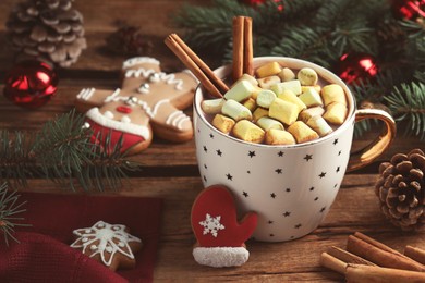 Photo of Delicious hot chocolate with marshmallows near Christmas cookies and decor on wooden table