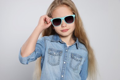 Girl in stylish sunglasses on light grey background