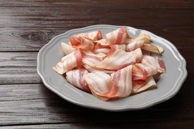 Photo of Slices of raw bacon on dark wooden table, closeup