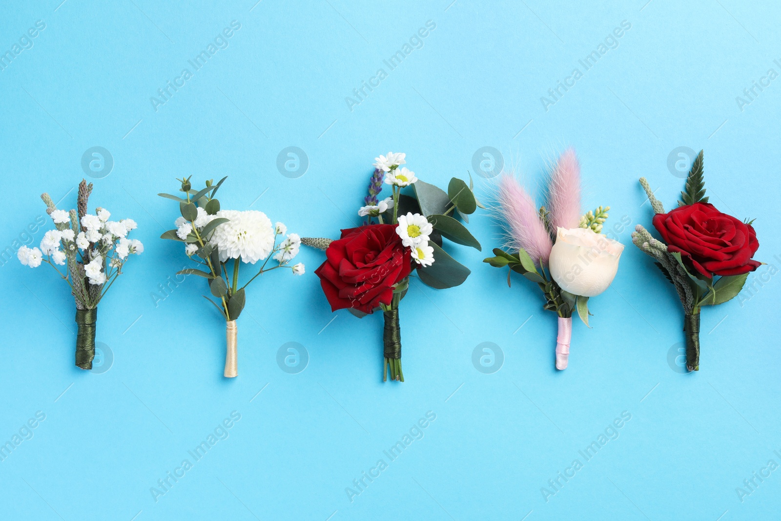 Photo of Many stylish boutonnieres on light blue background, flat lay