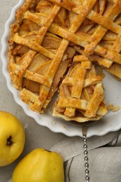 Photo of Tasty homemade quince pie with cake server and fresh fruits on light grey table, flat lay