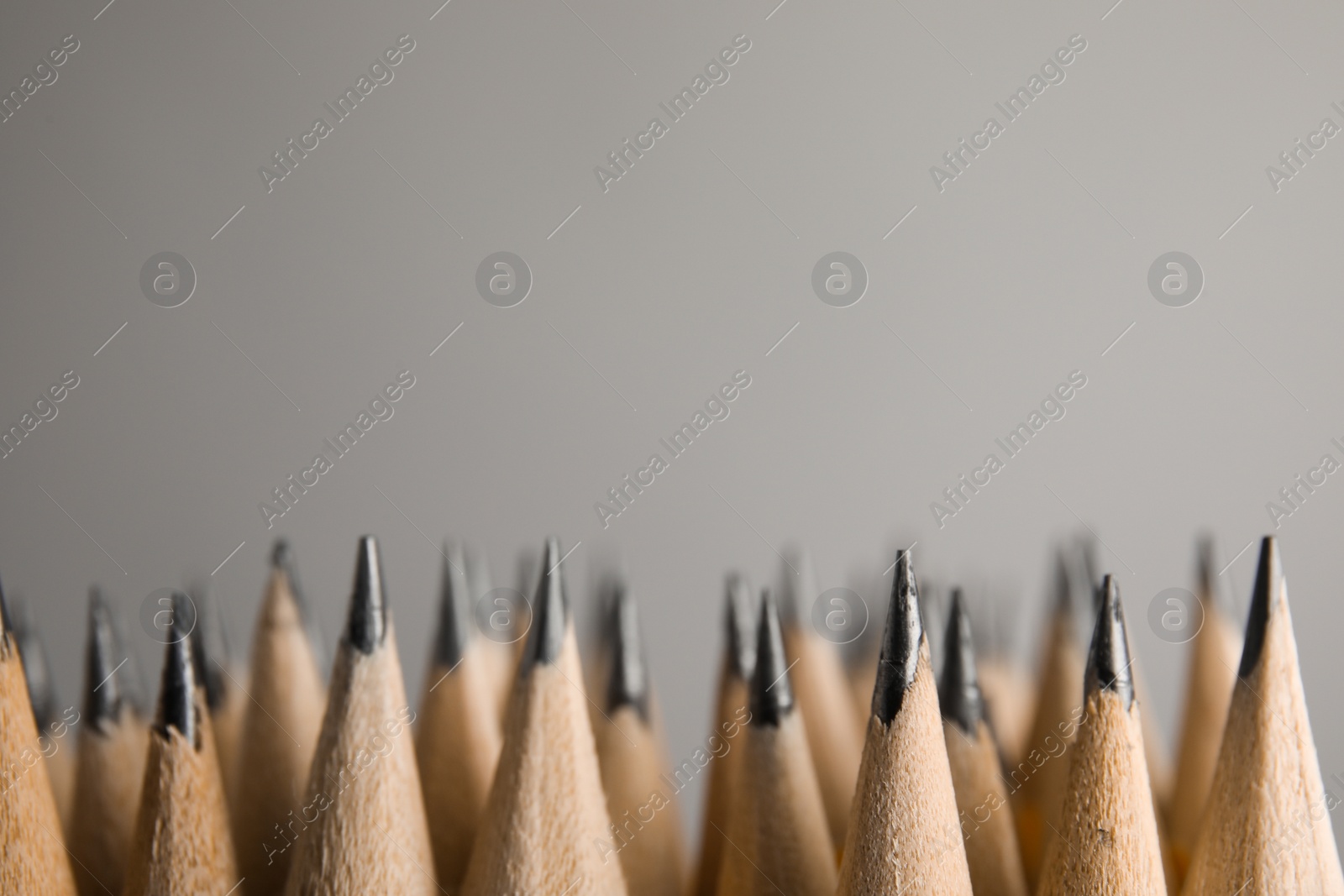 Photo of Many graphite pencils on grey background, closeup. Space for text