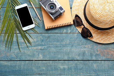 Photo of Flat lay composition with stylish hat, camera and smartphone on wooden background