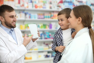 Photo of Professional pharmacist working with customer in modern drugstore