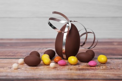 Photo of Delicious chocolate eggs and colorful candies on wooden table