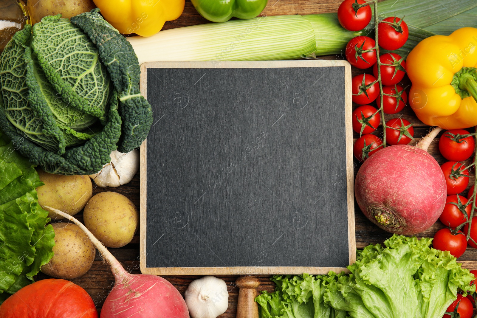 Photo of Blank chalkboard surrounded by different fresh vegetables on wooden table, flat lay with space for text. Cooking classes