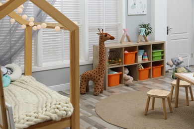 Photo of Cute child's room interior with toys and wooden furniture