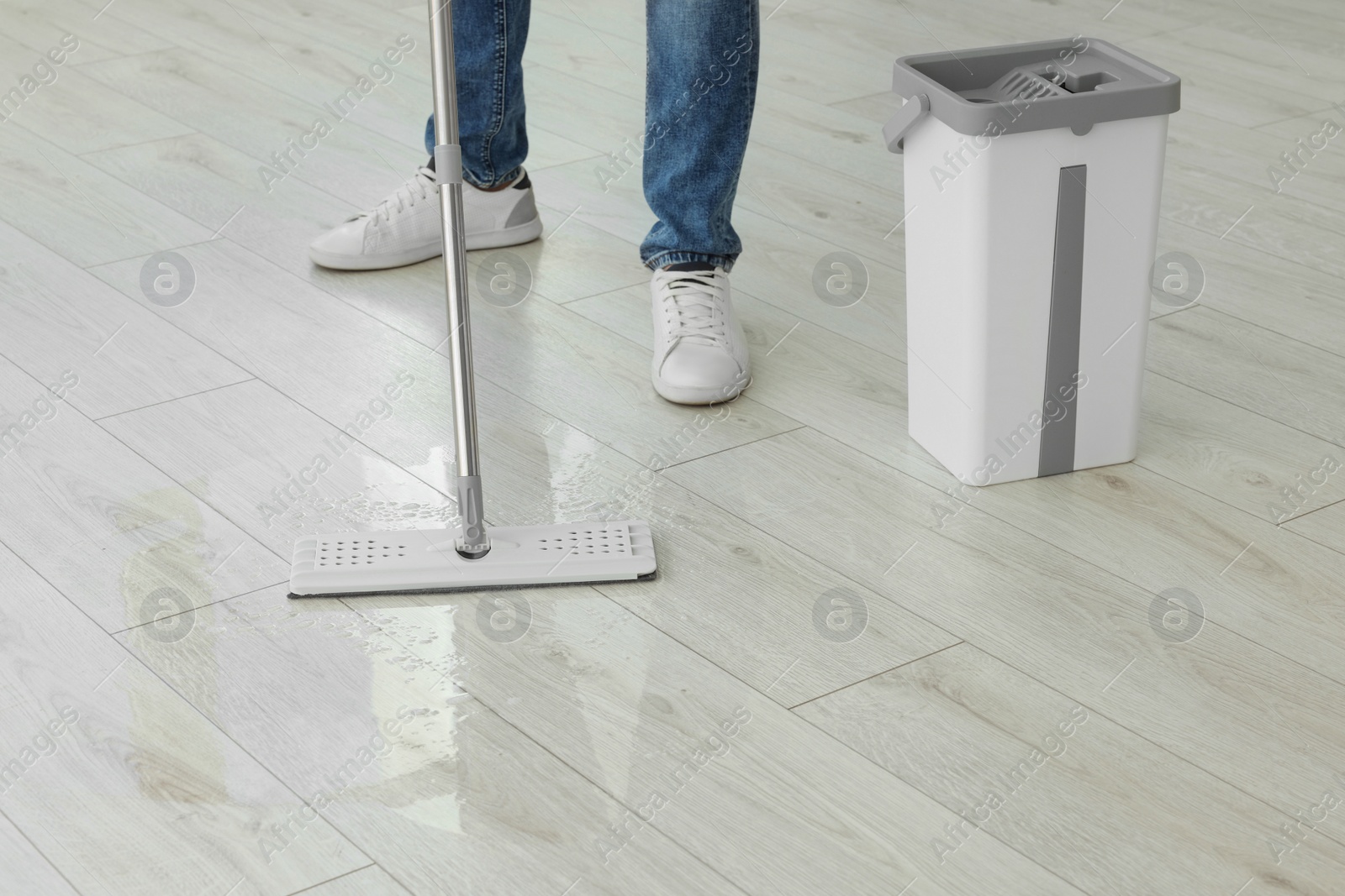 Photo of Man cleaning floor with mop indoors, closeup