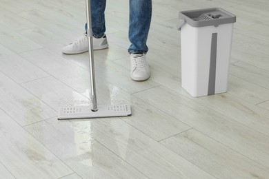 Photo of Man cleaning floor with mop indoors, closeup