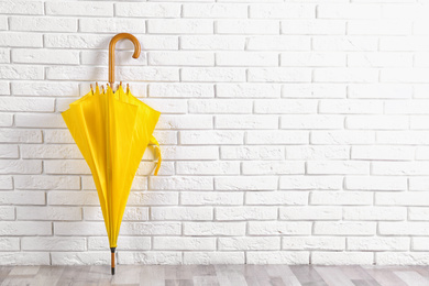 Photo of Beautiful yellow umbrella near white brick wall. Space for text