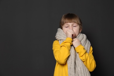 Cute little girl coughing against dark background. Space for text