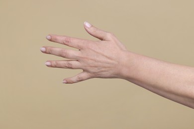 Photo of Closeup of woman's hand with aging skin on beige background. Rejuvenation treatment