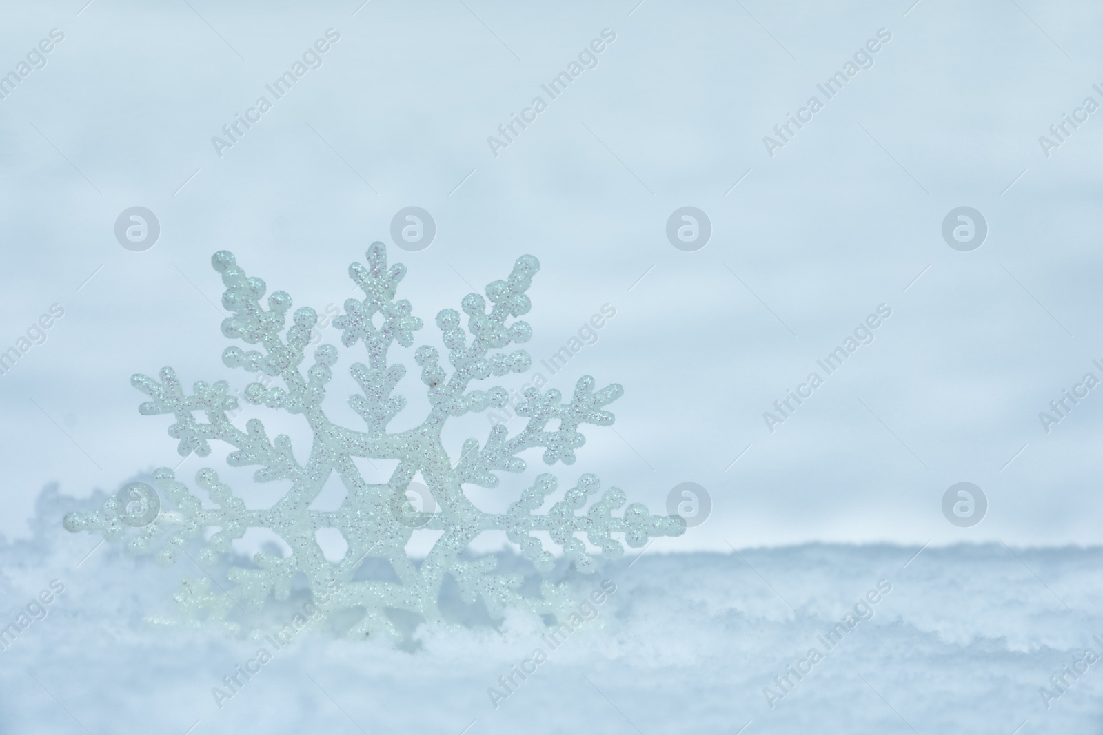 Photo of Beautiful decorative snowflake in white snow, outdoors. Space for text