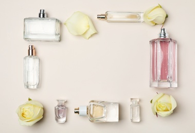 Flat lay composition with bottles of perfume and roses on light background