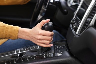 Woman using gear stick while driving her car, closeup