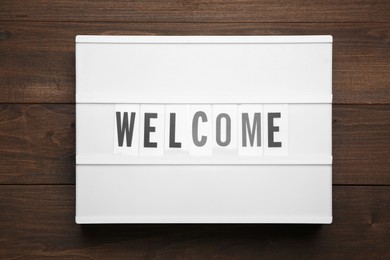 Lightbox with word Welcome on wooden background, top view