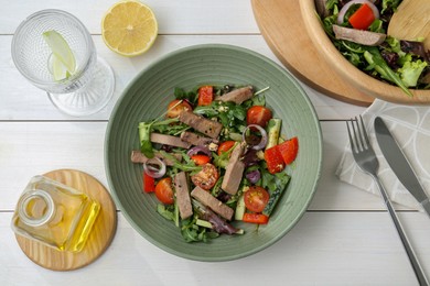 Delicious salad with beef tongue and vegetables served on white wooden table, flat lay