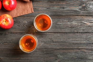 Glasses of apple juice on dark wooden background, top view