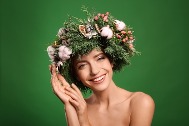 Happy young woman wearing wreath on green background