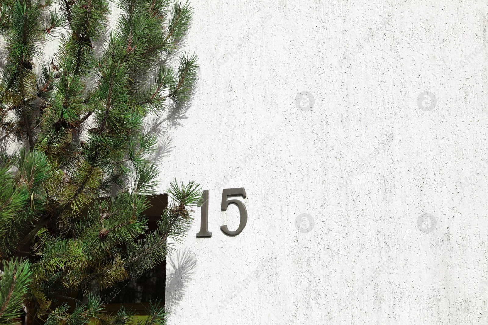 Photo of House number 15 on white textured wall outdoors. Space for text