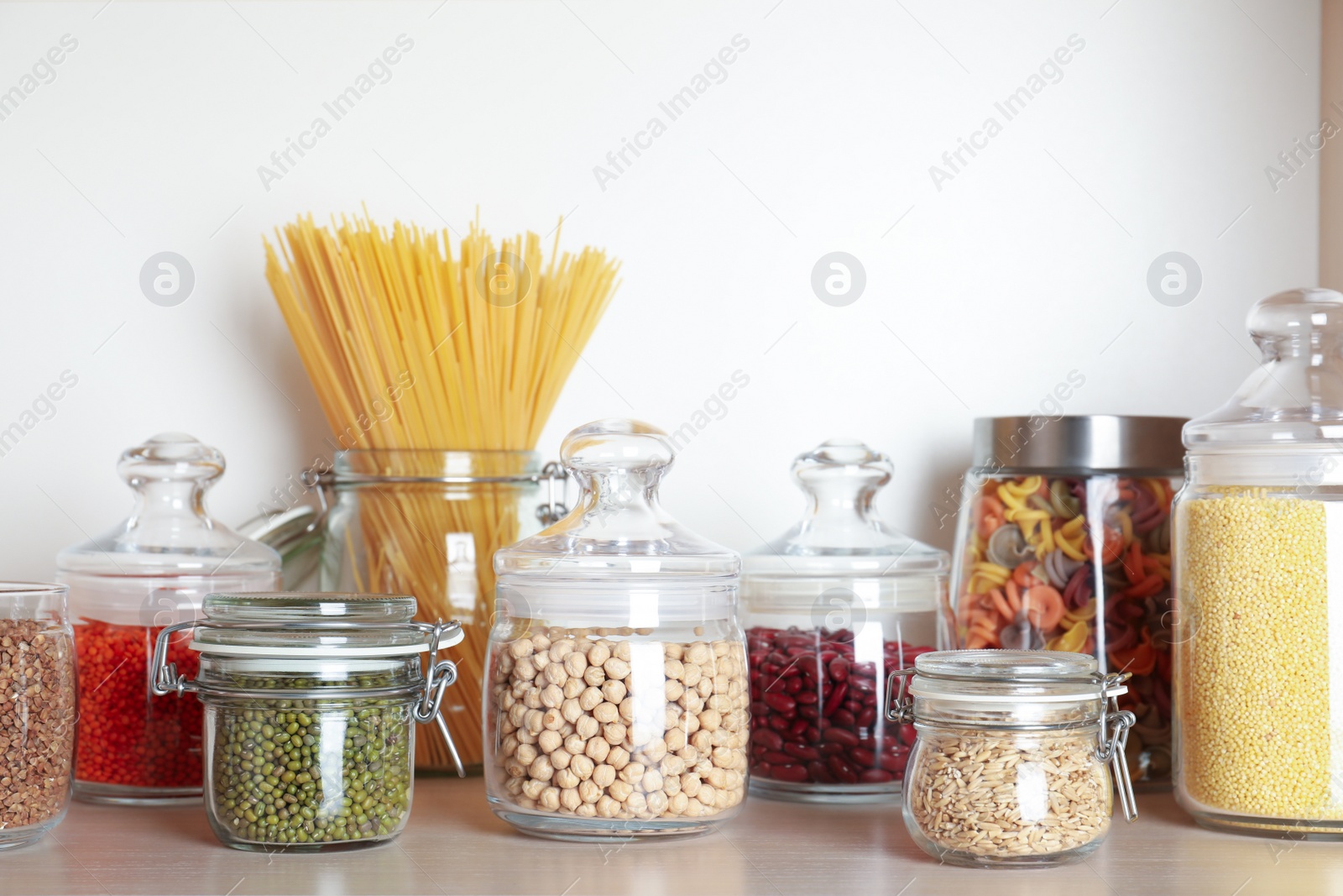 Photo of Glass jars with different types of groats on wooden shelf