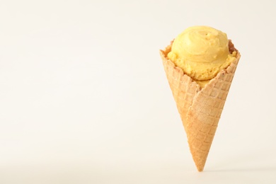 Photo of Delicious yellow ice cream in waffle cone on white background. Space for text