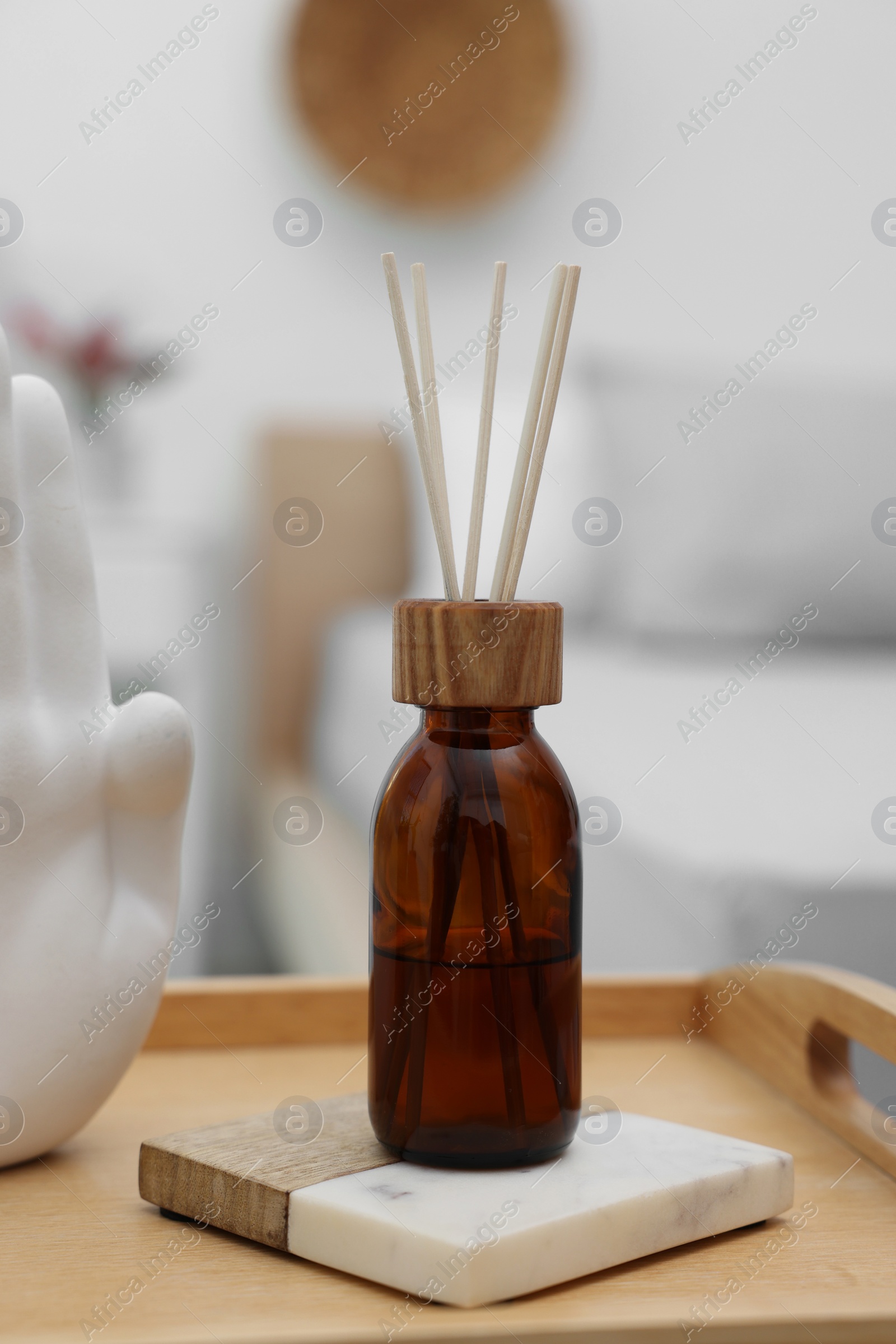 Photo of Aromatic reed air freshener on wooden tray indoors