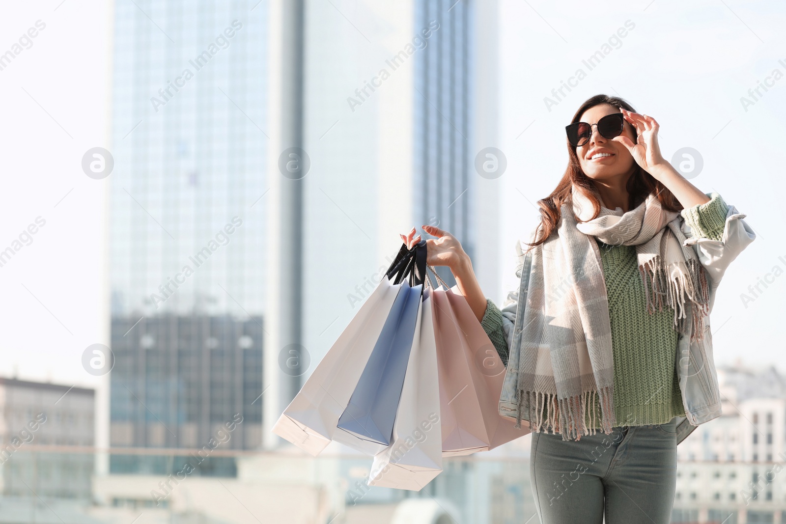 Photo of Beautiful young woman with shopping bags on city street