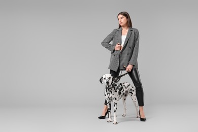 Photo of Beautiful young woman with her adorable Dalmatian dog on light grey background. Lovely pet