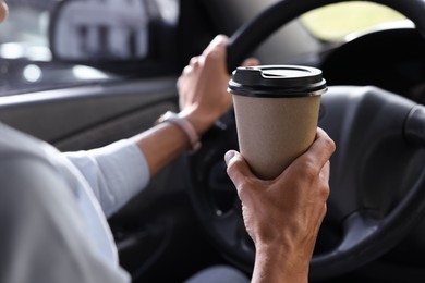 Photo of Coffee to go. Woman with paper cup of drink driving her car, closeup