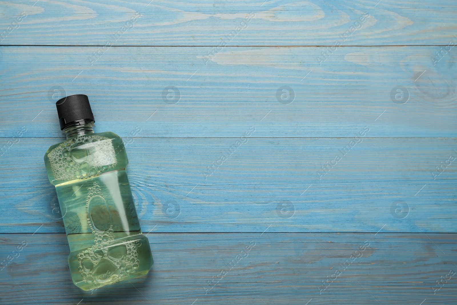 Photo of Mouthwash on turquoise wooden table, top view. Space for text